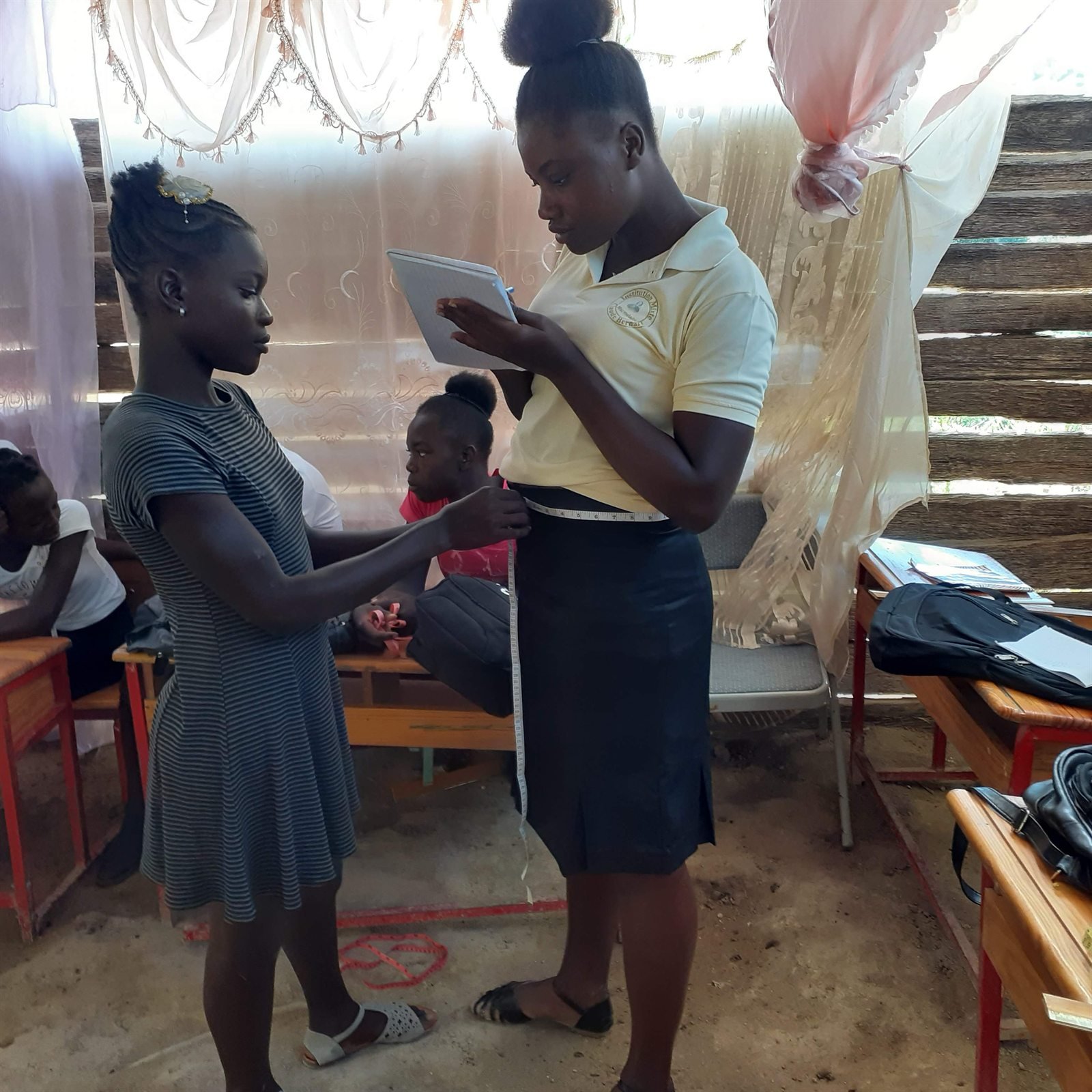 Une formatrice prend des mesures sur une participante pendant un atelier de couture.