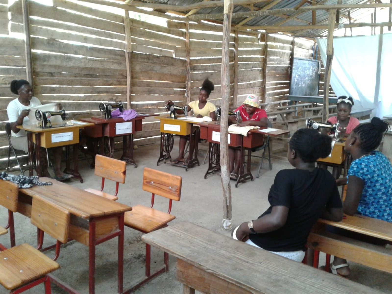 Groupe de participants dans une salle équipée de machines à coudre pendant une formation professionnelle.